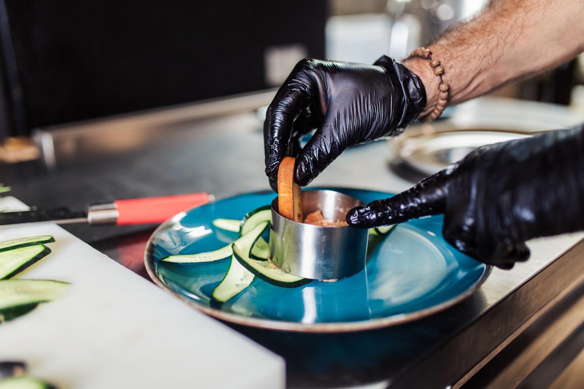 Chef hands arranging a plate with precision tools